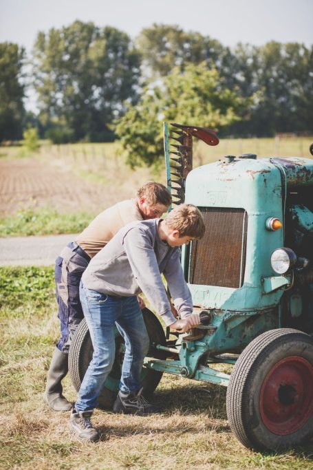 Mann und Junge werkeln auf einem Feld bei der Biberburg gemeinsam an einer alte Landmaschine